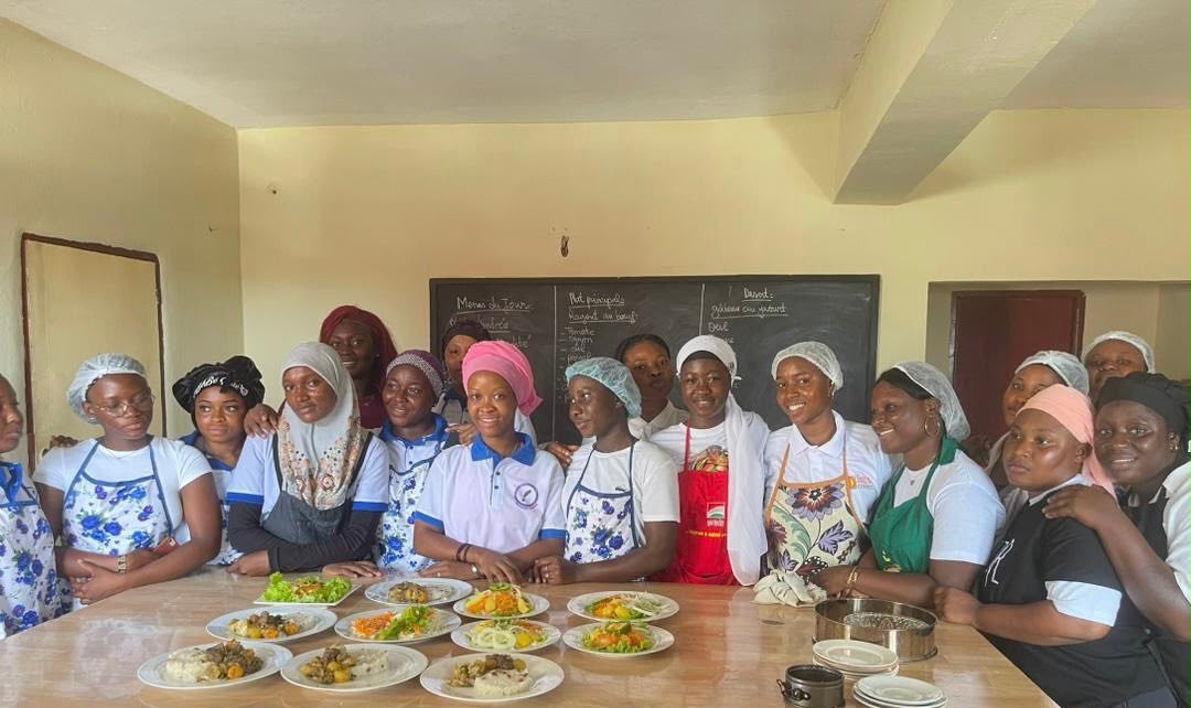 Groupe d'apprenantes d'ADEFOR en tenue de cuisine devant les plats préparés en atelier